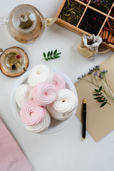 Homemade zephyr or marshmallow in white plate with cup of tea on white table. Marshmallow, Meringue, Zephyr. Valentine's or Mothers Day concept.