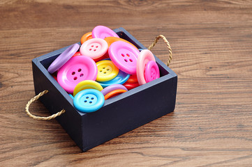 A blue bucket filled with colorful buttons in different sizes