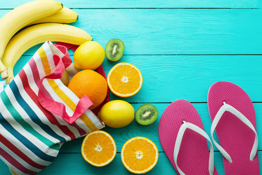 Summer fun time, flip flops and fruits on blue wooden background. Orange, lemon, kiwi, banana fruit , slippers on the floor. Top view and copy space