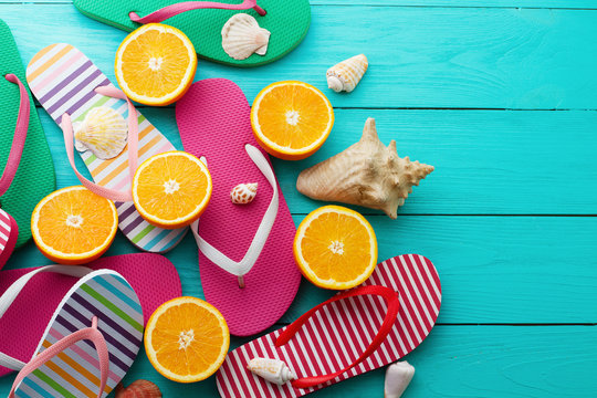Summer fun time and flip flops. Sea shell. Slippers and orange fruit on blue wooden background. Mock up and picturesque. Top view. Copy space