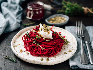 Roasted beetroot and thyme spaghetti with pumpkin seed in craft plate on dark tabletop. Ideas and...