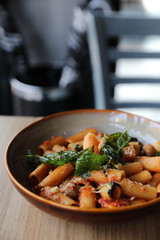 Pasta with sausage in tomato sauce on wood background , italian food