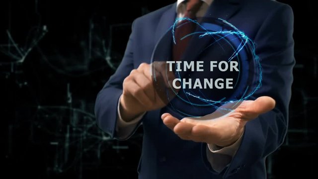 Businessman shows concept hologram Time for change on his hand. Man in business suit with future technology screen and modern cosmic background