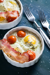 Baked eggs with cherry tomatoes, bacon and greens