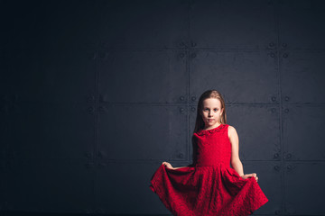 Obraz premium girl in red dress in studio on dark background. Copy space.