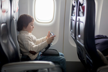 Cute six years old boy, playing on tablen in aircraft on board