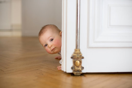 Little baby boy, toddler, in a long hall, crawling on the floor