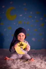 Little baby boy with cute teddy bear and moon on a blue star and moon background