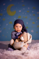 Little baby boy with cute teddy bear and moon on a blue star and moon background