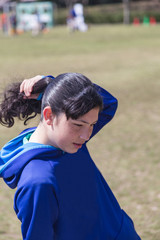 Naklejka premium Teenage girl enjoying a park and fixing her hair on a spring day.