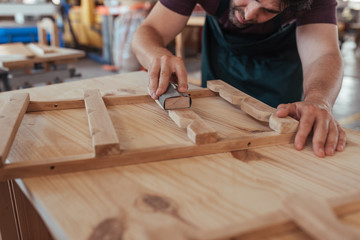Craftsman skillfully sanding a piece of wood in his workshop