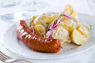 Foto auf Leinwand grilled sausage with classical potato salad with mayonnaise dressing on white backgound © eugenaklykova