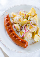 grilled sausage with classical potato salad with mayonnaise dressing on white backgound