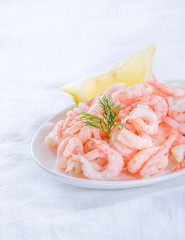 shrimps - cooked and peeled with lemon wedge on white