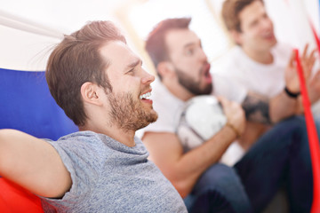 Obraz premium Happy male friends cheering and watching sports on tv