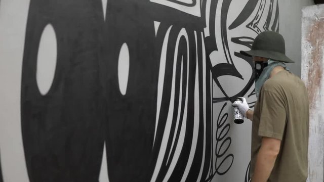 Graffiti artist paint spraying the wall, urban outdoors street art concept
