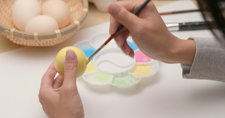 Obraz na płótnie Canvas Coloring eggs for Easter with hands and a brush with watercolor paints