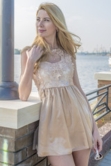 Young beautiful blond woman in a beautiful dress on the waterfront
