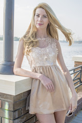 Young beautiful blond woman in a beautiful dress on the waterfront
