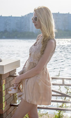 Fototapeta na wymiar Young beautiful blond woman in a beautiful dress on the waterfront 