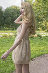Young beautiful blonde woman in a beautiful dress in a summer park
