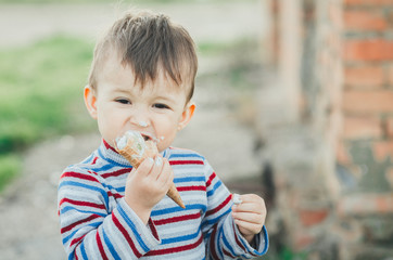 little cute boy eating ice cream three years very appetizing, amid nature, green grass