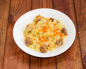Cooked pilaf on dish on wooden surface