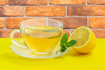 Tea with mint and lemon on a yellow surface