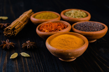  colorful spices in ceramic bowls on wooden table
