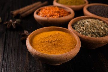  colorful spices in ceramic bowls on wooden table