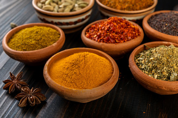 Different colorful spices in  spoons  on a dark  background.