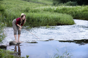 Fototapeta premium Girl by the river with a fishing rod