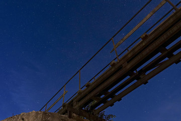 Night sky with many stars before sunrise. View from under the old bridge. - obrazy, fototapety, plakaty