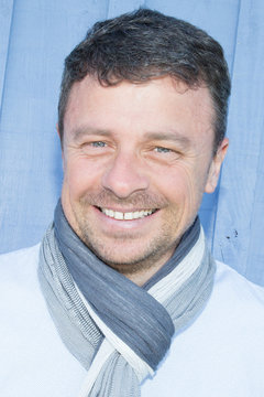 Close Up Portrait Of Handsome Older Man In Blue Shirt And Scraf With Big Smile On His Face