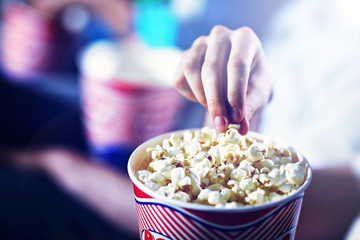 Male hand taking popcorn from the box in the cinema - obrazy, fototapety, plakaty