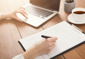 Closeup of woman hands typing on laptop and writing