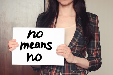 Girl holds a paper sheet with text no means no
