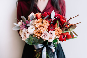 Very nice young woman holding big and beautiful colourful flower wedding bouquet held red half pastel coloured with roses,ranunculus and eucalyptus