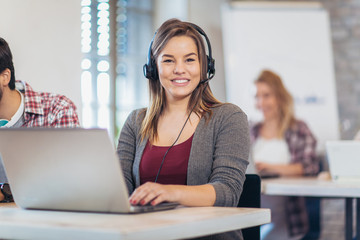 Portrait of happy smiling female customer support phone operator at workplace.