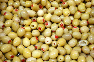 Salted green olives stuffed with red pepper as background.  