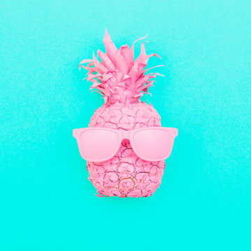 painted pink pineapple in sunglasses on the background of turquoise. minimalism and creative conceptual surrealism