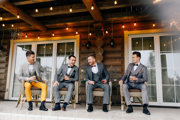 groom and friends sit on the terrace of the house and laugh