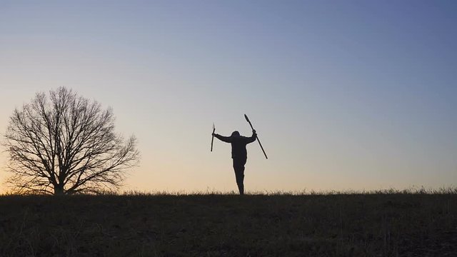 A satisfied farmer dances ib the field. Silhouette of a sunset or sunrise in field. slow motion