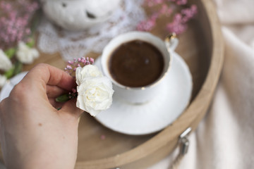 Female hands hold a white flower and pink. Breakfast in bed. Flavored coffee. Delicate light colors. Romance. Place for text
