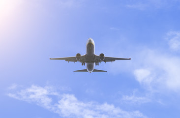 Front view of a big jet plane taking off on blue cloudy sky background