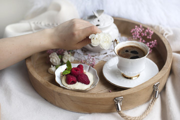 Fragrant coffee, flowers in female hands. Breakfast in bed on a wooden tray. Romance