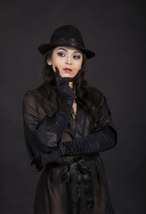 Beautiful young girl in black tunic, black gloves and black hat.