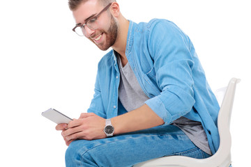 Young man sitting on chair and using mobile phone. Startupper. Young entrepreneur.