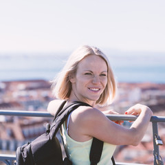 Traveller female on the background of the panorama of Lisbon. Young pretty girl, sunrise time, happy face woman, cute, attractive.