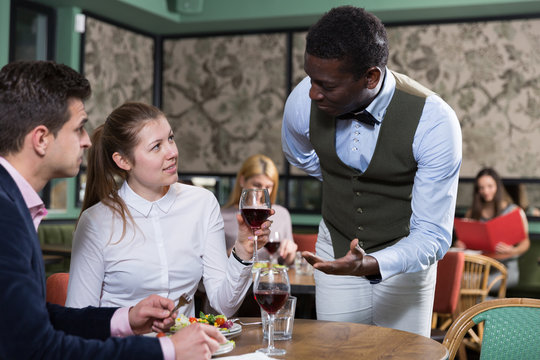 African American waiter talking with young couple